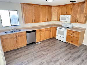 Kitchen with white appliances, light countertops, and light wood-style floors
