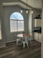 Dining space featuring vaulted ceiling and dark wood-type flooring