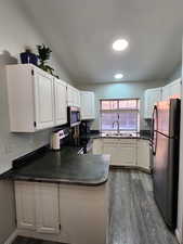 Kitchen with dark countertops, white cabinetry, a peninsula, and appliances with stainless steel finishes