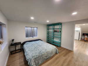 Bedroom with recessed lighting, light wood-style floors, and white refrigerator