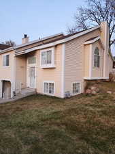Rear view of house with a chimney and a yard
