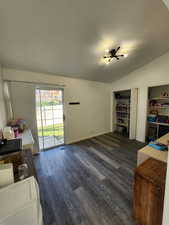 Office area with lofted ceiling, dark wood-style flooring, and a textured ceiling