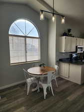Dining room featuring vaulted ceiling and dark wood-style flooring