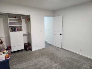 Carpeted bedroom with a closet and baseboards