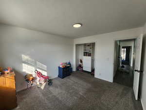 Bedroom featuring a closet, a textured ceiling, and dark colored carpet