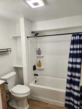 Bathroom with a textured ceiling, shower / tub combo, wood finished floors, and vanity