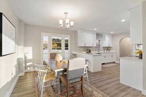 Dining room featuring light wood finished floors, arched walkways, a chandelier, and recessed lighting