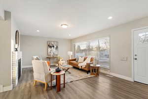 Living room featuring wood finished floors, a brick fireplace, and recessed lighting