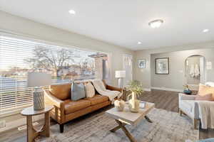 Living room with arched walkways, wood finished floors, and recessed lighting