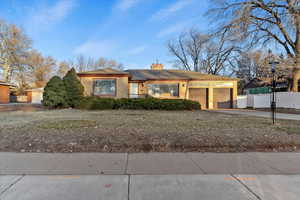 Ranch-style house featuring brick siding, a chimney, driveway, an attached garage, and a gate