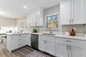 Kitchen featuring white cabinetry, a peninsula, stainless steel dishwasher, light stone counters, and recessed lighting