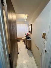 Bathroom featuring a textured wall, a textured ceiling, and light floors