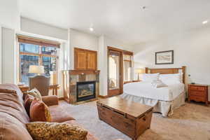 Bedroom featuring light carpet and a tile fireplace