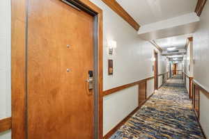 Corridor featuring ornamental molding and a textured wall