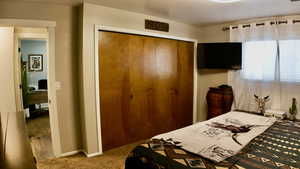 Carpeted bedroom with a closet.