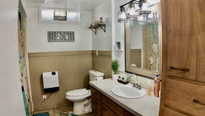 Full bath featuring a wainscoted wall, vanity, a shower with curtain, and light tile patterned floors