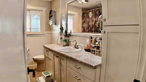 Bathroom with vanity, curtained shower, a wainscoted wall, and light tile patterned flooring