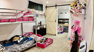 Bedroom with light colored carpet and a barn door