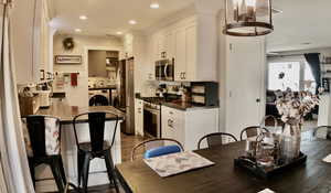 Kitchen with appliances with stainless steel finishes, white cabinets, dark countertops, independent washer and dryer, and LVP finished floors