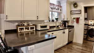 Kitchen featuring tasteful backsplash, washer / clothes dryer, dark countertops, and dark wood-type flooring