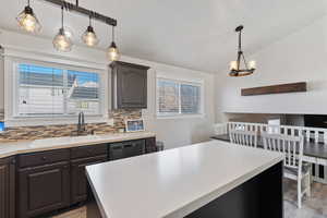 Kitchen featuring pendant lighting, light countertops, a kitchen island, healthy amount of natural light, and lofted ceiling