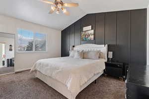 Carpeted bedroom with lofted ceiling, a ceiling fan, a decorative wall, and an accent wall