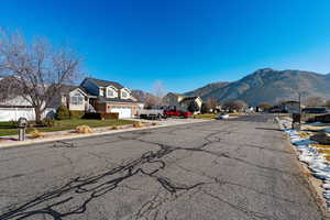 View of asphalt street featuring sidewalks, curbs, a residential view, and a mountain view