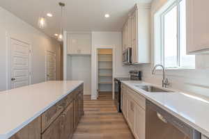 Kitchen with stainless steel appliances, decorative light fixtures, recessed lighting, white cabinets, and light stone counters