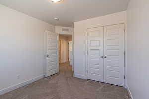 Unfurnished bedroom with a closet, light colored carpet, and a textured ceiling