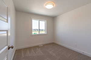 Empty room with carpet and a textured ceiling