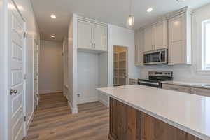 Kitchen featuring appliances with stainless steel finishes, light stone counters, light wood finished floors, recessed lighting, and hanging light fixtures