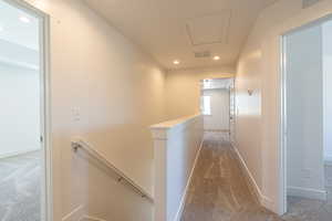 Hallway featuring an upstairs landing, dark carpet, and recessed lighting
