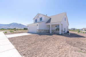 View of front facade featuring a mountain view, stone siding, driveway, an attached garage, and a shingled roof