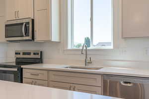 Kitchen with stainless steel appliances, light stone counters, and gray cabinetry