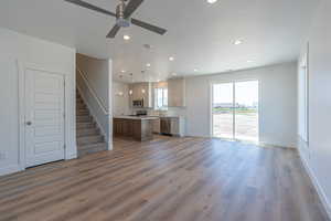 Unfurnished living room featuring stairs, dark wood-style flooring, recessed lighting, ceiling fan, and a textured ceiling