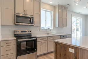 Kitchen with stainless steel appliances, light wood-style floors, light stone counters, and recessed lighting