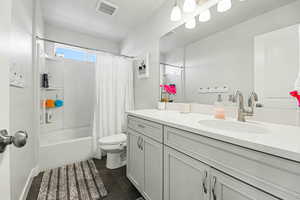 Full bathroom with vanity, shower / bath combo, and dark tile patterned flooring