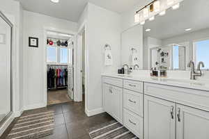 Bathroom with a walk in closet, a stall shower, double vanity, plenty of natural light, and recessed lighting