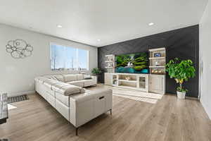 Living area featuring an accent wall, light wood-style floors, and recessed lighting