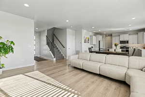 Living area with stairs, recessed lighting, and light wood-style flooring