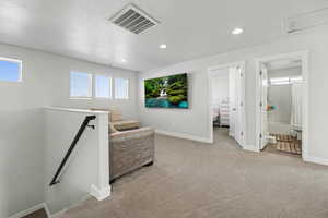Living area with an upstairs landing, light colored carpet, a textured ceiling, and recessed lighting