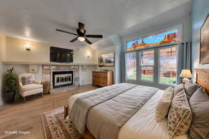 Bedroom featuring oak floors, a fireplace, and beautiful windows
