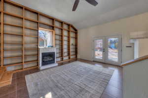 Great room featuring built in bookcases, plenty of natural light, new tile flooring, vaulted ceiling, and a fireplace