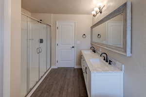 Bathroom featuring double vanity, a stall shower, and LVP flooring