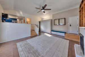 Great room with stairway, ceiling fan, lofted ceiling, and new tile flooring