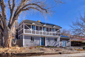 View of front of house featuring roof mounted solar panels, brick & stucco exterior, and french doors