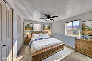 Bedroom with light carpet, a ceiling fan, and multiple closets