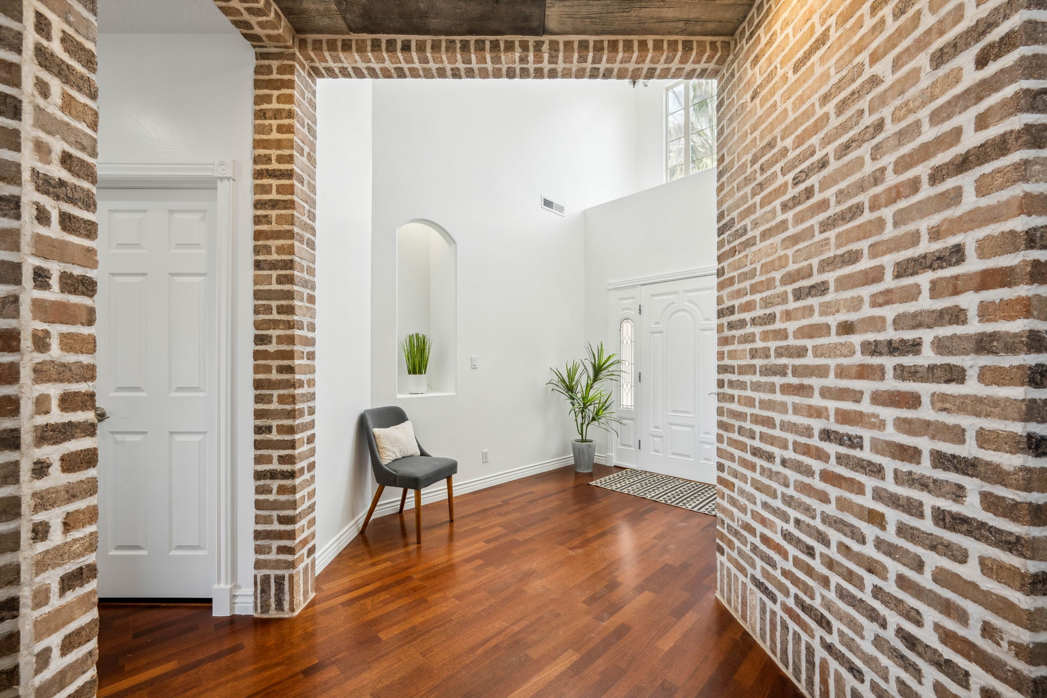 Living area with brick wall, a towering ceiling, and dark wood-type flooring
