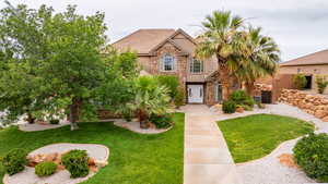View of front of property with stone siding, stucco siding, and a front yard