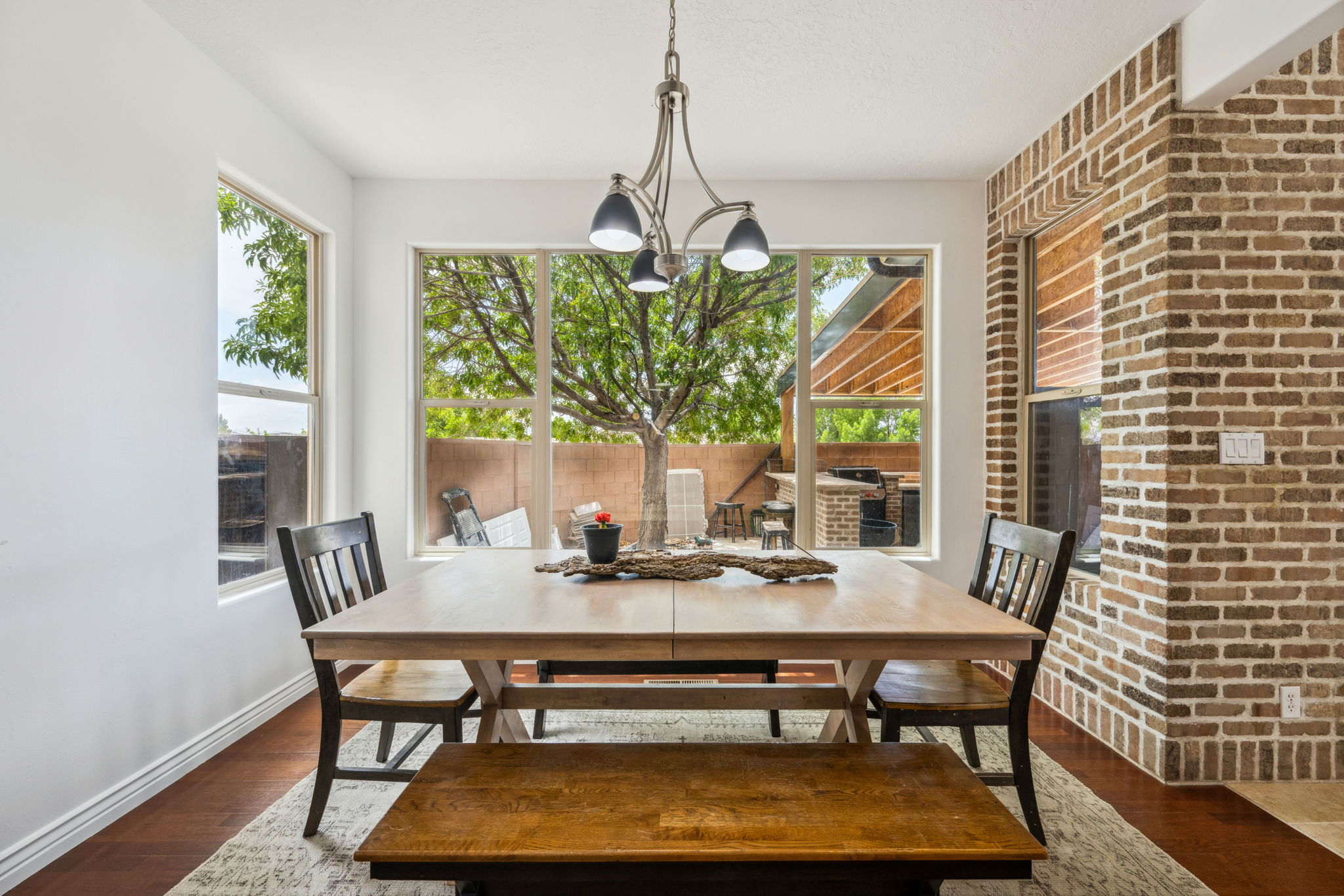 Dining area with brick wall, dark wood-style flooring, and a chandelier
